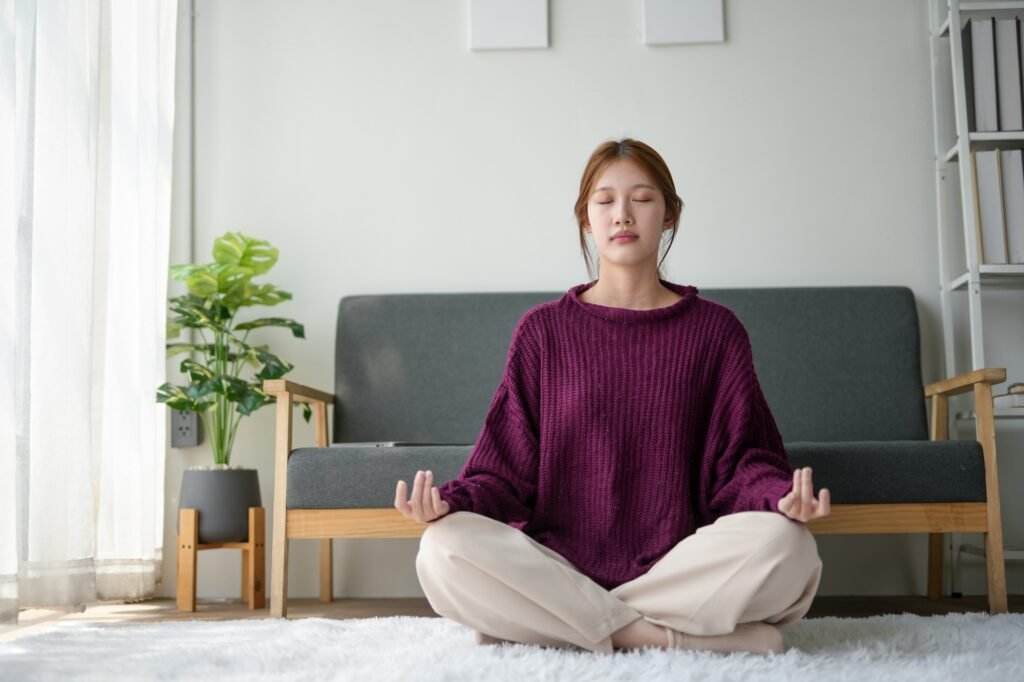 Woman practicing meditation at home, sitting on the floor with eyes closed